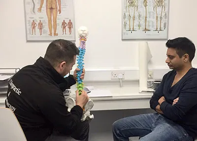 Chiropractor explaining a spine model to a patient at MGM Clinics