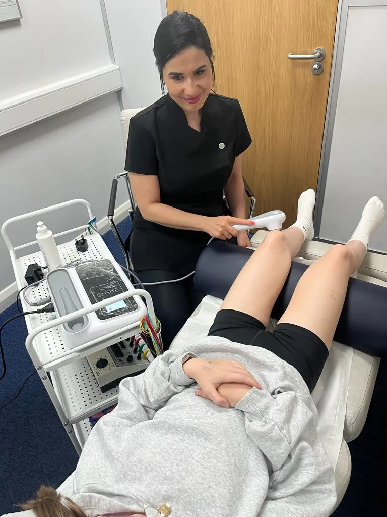 Physiotherapist treating a patient's leg with a therapy machine